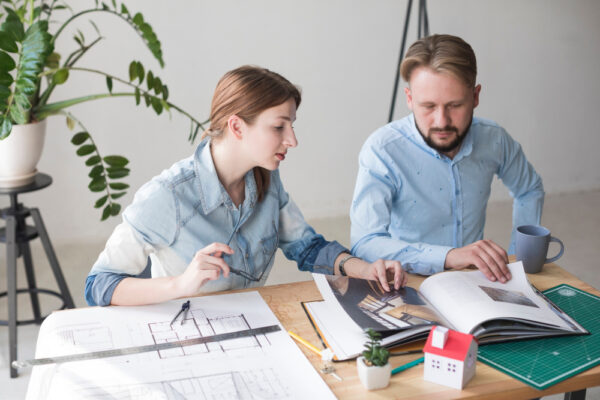 A home design-build company team reviews detailed blueprints with their clients